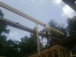 Carpenter setting a ridge beam over a new addition frame — Ice Dam Removal by Roofing Brothers in Lynnville