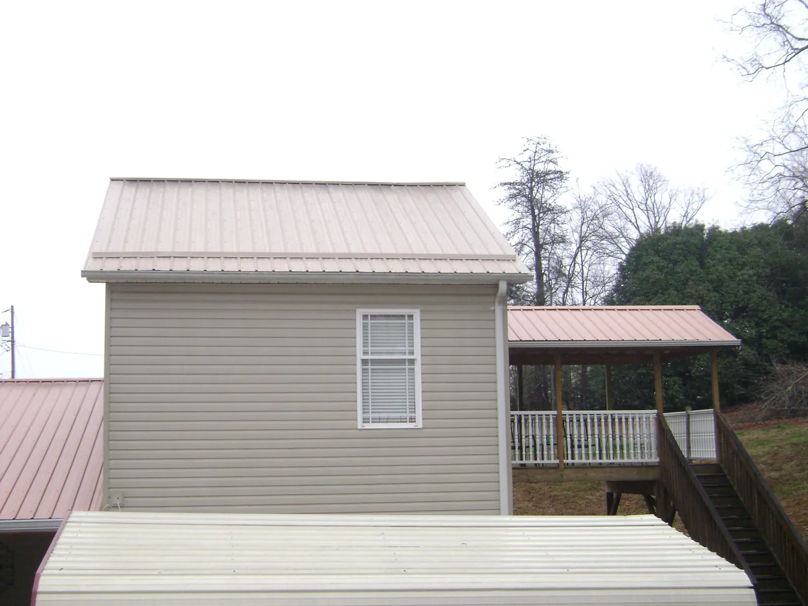 Tan metal roofs on a two story addition and attached porch, from a Roof Replacement job in Lynnville