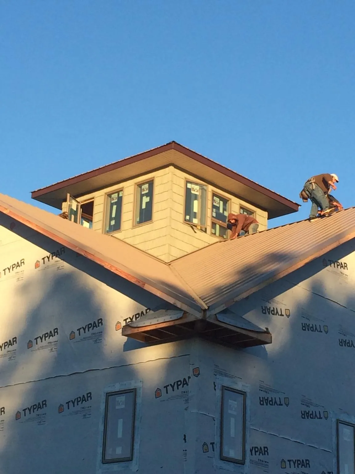 Roofers working around a rooftop cupola on a new metal roof at sunset — Roof Waterproofing in Lynnville by Roofing Brothers